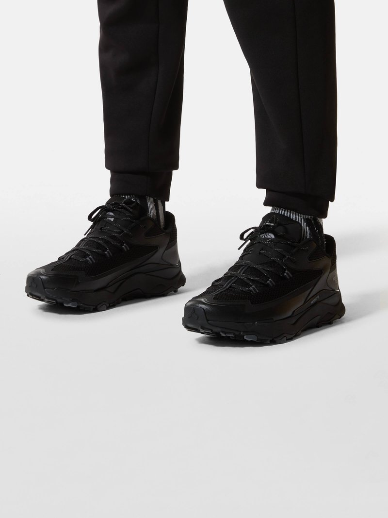 Black athletic shoes with a textured mesh upper, reinforced toe, and rubber outsole. Features laces and padded collar for comfort.