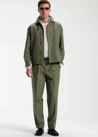 Olivgrön, lätt jacka med knappstängning, två bröstfickor; matchande byxor; vit skjorta under; svarta skor; solglasögon.