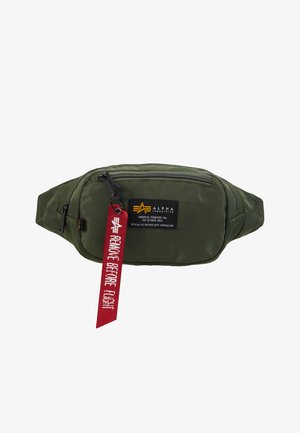 Maslinasto zelena najlonska torbica s prednjim zip džepom, crnom oznakom i crvenom oznakom "Uklonite prije leta". Kompaktni, elegantni dizajn.