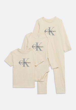 Tri béžové detské odevy Calvin Klein, vrátane trička s krátkym rukávom, body s dlhým rukávom a dlhého overalu bez nožičiek s dlhým rukávom.