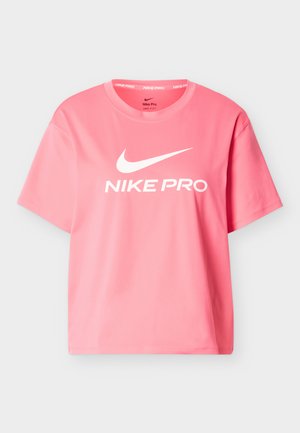 Różowa koszulka Nike Pro z krótkim rękawem, wykonana z gładkiego materiału. Na przodzie znajduje się biały nadruk z logo, okrągły dekolt. Standardowy krój.