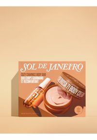 El dúo corporal Cozy Cravings incluye una botella de spray transparente y un tarro de crema redondo, ambos con un empaque de tonos cálidos y una textura suave.