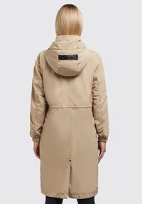 Beige langer Puffer-Mantel mit Kapuze, elastischen Bündchen und einem Kordelzug in der Taille. Verfügt über ein KHUJO-Logo auf dem Rücken und ein Rückenbelüftungsdetail.