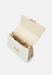 Weiße strukturierte Handtasche mit einem goldenen Verschluss, stoffähnlicher Außenseite, beigem Innenfutter und flachem Design. Geöffnet, um das Innere des Fachs zu zeigen.