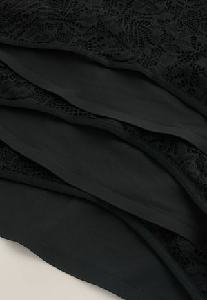 Zwarte kanten stof gelegd over een glad zwart materiaal, met een bloemachtig patroon en een dunne zwarte rand langs de randen.