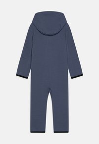 Mono azul marino con capucha, mangas largas y ribetes negros en los puños. Fabricado con un material suave y texturizado, diseñado para la comodidad.