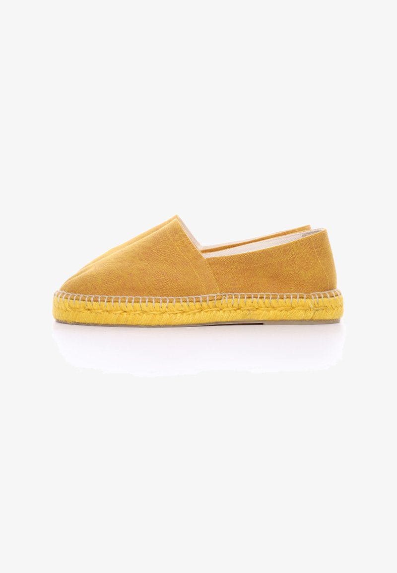 Zapato deslizante de tela amarilla con punta afilada y suela de yute natural. Presenta costuras a lo largo de la suela y un diseño simple y minimalista.