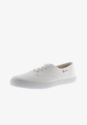 Sneakers bianchi in tela con punta rotonda, design con lacci, suola in gomma testurizzata e un sottile accento di branding. Finitura in tessuto liscia.