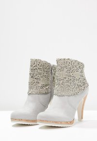 Gray suede ankle boots with a decorative lace cuff, high heel, and cork accent on the sole, featuring a side zipper for easy wear.