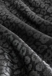 Czarna tkanina w wzory z subtelną teksturą, z kwiatowym motywem przerywanym małymi kropkami, co nadaje głębi i wizualnego zainteresowania.