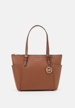Brązowa skórzana torba typu tote Michael Kors z dwoma paskami na ramię, bocznymi kieszeniami oraz złotym zawieszką z logo MK wiszącą przy górnym zamku.