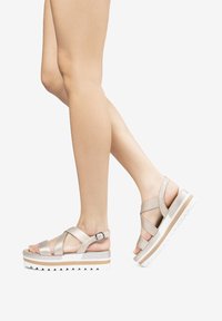 Sandali leggeri color beige con cinturino, dotati di una suola a piattaforma con strisce bianche e beige, suola testurizzata e fibbia regolabile sulla caviglia.