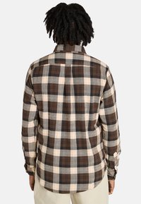 Camisa de cuadros marrón y crema con mangas largas, cuello con botones y un ajuste relajado. Tejido texturizado con cuadros en contraste.