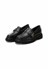 Zapatos de piel negra con una suela gruesa, que presentan un detalle de correa con hebilla y un acabado suave. Punta redondeada y sutilezas en las costuras.