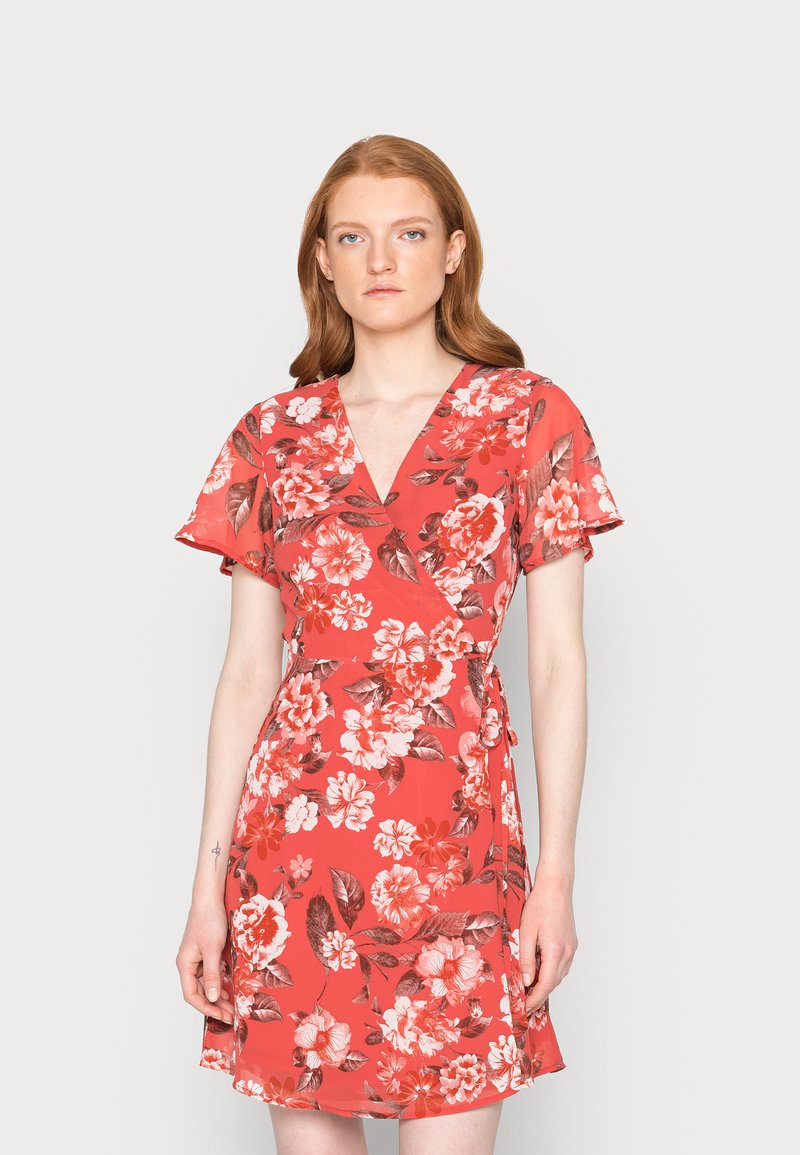 Vestido envolvente vermelho com flores, apresentando mangas curtas, um decote em V profundo e cintura ajustada com laço. O tecido tem uma textura suave com grandes padrões de flores contrastantes.