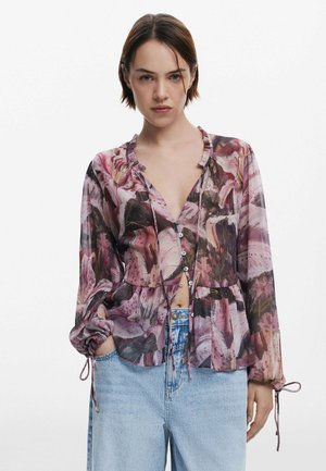 Short-sleeve, loose-fit blouse in sheer fabric with a multicolored floral pattern. Features a ruffled neckline and buttons down the front.