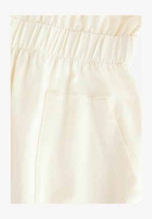 Beige bomullstyg med elastisk midjereså. Slät textur, minimal sömdetalj och avslappnad passform.