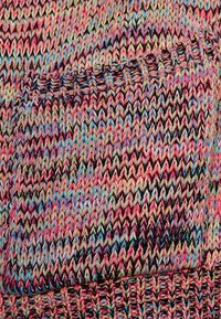 Flerfärgad stickad tyg med ett chevronmönster i rosa, blå och beige nyanser. Inkluderar en liten fickdetalj.