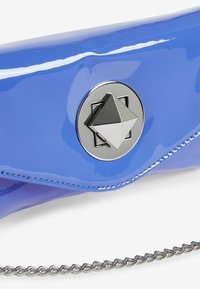 Borsa a mano in vernice blu con una fibbia geometrica argento, design elegante e tracolla metallica. Texture liscia con finitura lucida.