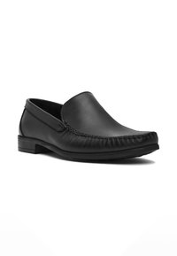 Zwarte leren slip-on loafer voor heren met gestikte teenafwerking en lage gestapelde hak op een witte achtergrond.