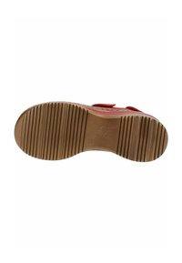 Sola di scarpa rossa con superficie in gomma marrone liscia, caratterizzata da scanalature orizzontali e marcature in rilievo. Dettaglio della chiusura in velcro visibile.