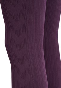 Strumpbyxor i en rik lila färg med ribbat mönster och chevrontyr längs sidorna, vilket ger en figurnära design.