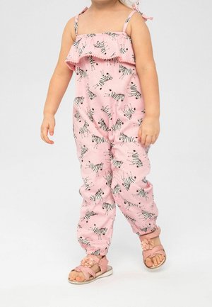 Salopette rose avec imprimé zèbre, dotée d'un haut à volants et de bretelles ajustables. Le tissu est léger, associé à des sandales roses.