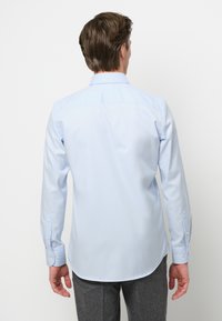 Lichtblauw overhemd met lange mouwen, voorzien van eengetailleerde pasvorm, knoopmanchetten en een gebogen zoom, gemaakt van glad, geweven stof.