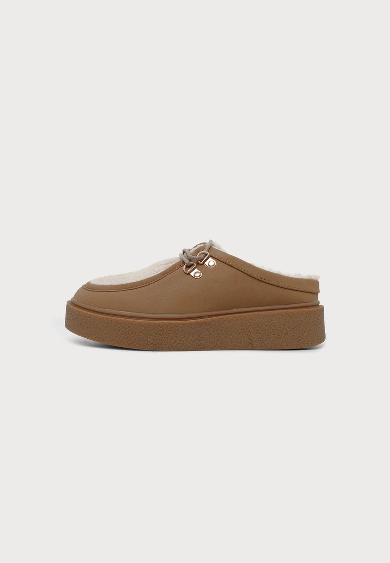 Chaussure marron à enfiler avec semelle épaisse, doublure polaire beige et œillets métalliques avec lacet sur fond blanc uni.