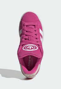 Ružičaste suede tenisice s bijelim prugama, vezanje na vezicu, okrugli vrh i veliki emblem na jezičku. Mekana unutrašnjost i gumeni potplat.