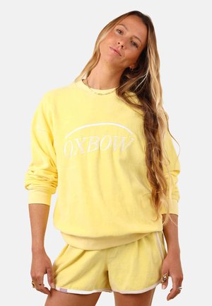 Sweatshirt en polaire jaune avec "OXBOW" brodé en blanc, associé à un short assorti avec des bordures blanches et une texture douce.