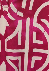 Živě růžová látka s výraznými bílými geometrickými vzory. Hladká textura s výstřihem do V a detailními prvky v potisku.