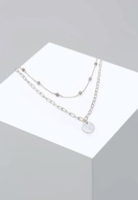 Lag en lagdelt sølvhalskæde med en kæde og perlestreng, med en rund vedhæng knyttet til, der viser en glat overflade og subtil tekstur.