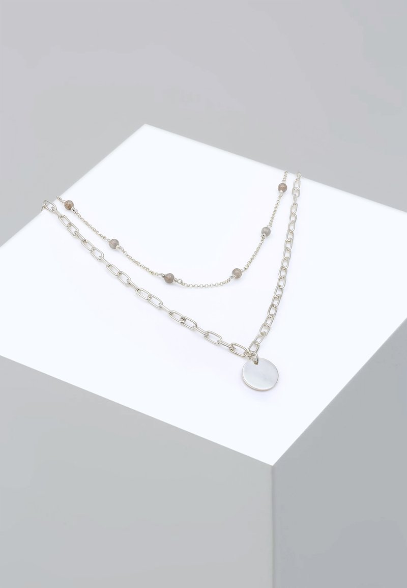 Lag en lagdelt sølvhalskæde med en kæde og perlestreng, med en rund vedhæng knyttet til, der viser en glat overflade og subtil tekstur.