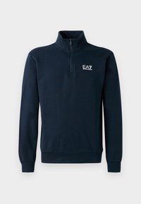 Mørkeblå genser med glidelås i kragen, lange ermer, ribbekant i ermene og et brodert logo på brystet. Myk tekstur.