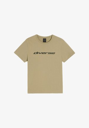 Beżowa koszulka z krótkim rękawem i okrągłym dekoltem z czarnym napisem „diverse” w nowoczesnej, małej czcionce umieszczonym na środku klatki piersiowej.