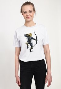 Biała bawełniana koszulka z grafiką przedstawiającą postać w czarnym ubiorze z łukiem, podkreśloną akcentami w kolorze żółtym i szarym.