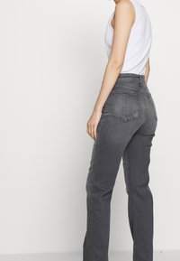 Gray high-waisted jeans with a straight-leg design, featuring a textured fabric, rear pockets, and minimal stitching accents.
