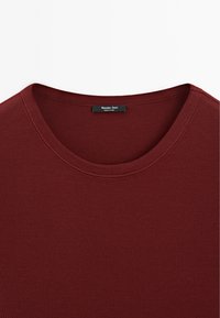 Burgundy crew neck t-shirt made from smooth fabric with ribbed texture and a label at the collar reading "Massimo Dutti."