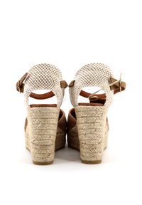 Sandali a zeppa marroni con una piattaforma in juta, dettagli in pelle color crema e una parte superiore intrecciata. Presentano cinturini regolabili sul retro per una vestibilità sicura.