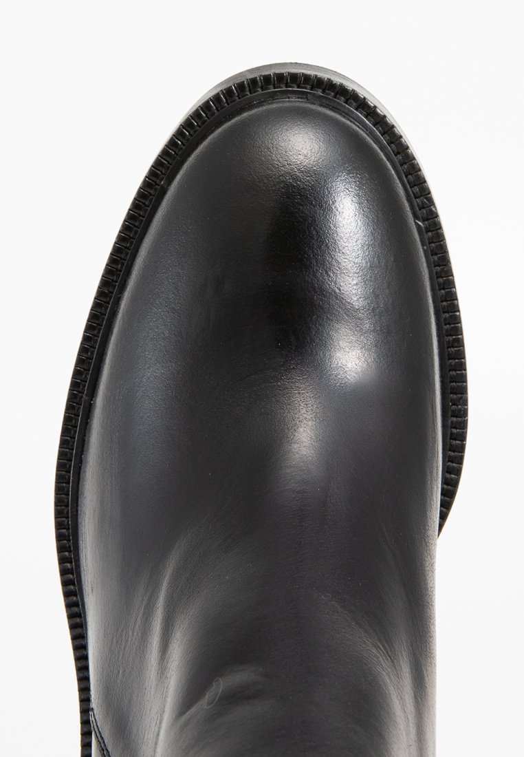 Stivale in pelle nera con una superficie liscia e lucida e una suola testurizzata. Punta tonda con una cucitura dettagliata lungo il bordo.