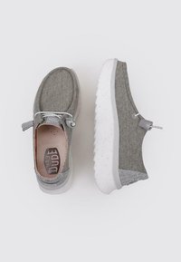 Zapatos de tela grises con un diseño texturizado, punta redonda y suela salpicada de blanco. Presenta cordones y un acento en el talón gris.