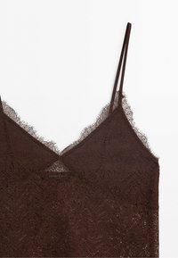 Brown lace camisole top with thin straps and delicate scalloped edges on a white background.