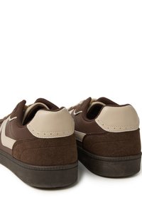 Sneaker marroni con una tomaia in pelle martellata e suede. Le caratteristiche includono un tallone beige chiaro, dettagli bianchi a contrasto e una suola in gomma.