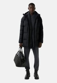 Schwarze Pufferjacke mit Kapuze, grauer Schal, dunkles Shirt und Hose. Hält eine schwarze Tasche. Klobige schwarze Stiefel. Einfaches Design und Texturen.