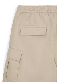 Pantalons cargo beiges avec une taille élastique, poches latérales et arrière, et une texture lisse et durable.