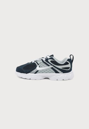 Μαύρο και γκρι αθλητικό παπούτσι Nike με λευκό λογότυπο Swoosh, λευκή σόλα, επάνω μέρος από πλέγμα και ύφασμα, και ταινία έλξης στη φτέρνα.