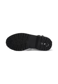 Zwarte rubberen zool met diepe profielpatronen, voorzien van ronde lugs voor grip. Gladde middensectie voor stabiliteit.