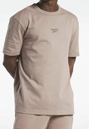 Beige katoenen t-shirt met een ronde hals en korte mouwen. Voorzien van een klein Reebok-logo geborduurd op de borst. Zachte textuur.