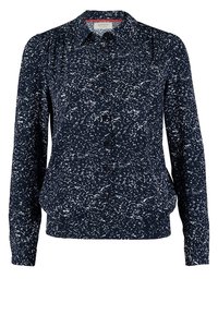 Blouse bleu marine à manches longues avec un motif à pois blancs, devant à boutons et col classique.